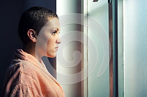 Young depressed cancer patient in front of hospital window