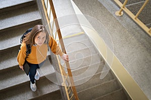 Young depressed lonely female college student walking down the stairs at her school, looking up at the camera.