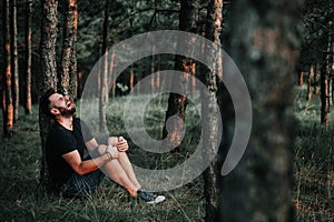 Young depressed man sitting alone in the woods