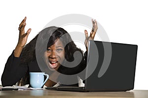 Young depressed and overwhelmed black African American business woman working frustrated at office computer desk feeling upset and