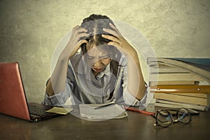 Young depressed and stressed Asian Korean student girl working with laptop and book pile overwhelmed and frustrated preparing exam