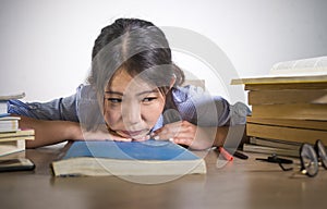 Young depressed and stressed Asian Korean student girl working with laptop and book pile overwhelmed and frustrated preparing exam