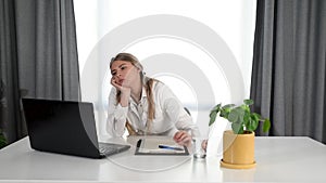 Young depressed woman doctor sitting in office room at the hospital taking a break from stressed work. Female medical worker under