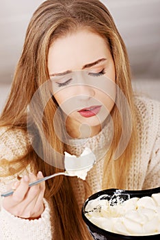 Mladý deprimovaný žena je jesť veľký misa z krémy na pohodlie seba 
