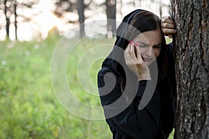 A young depressed woman is sad by a tree in the Park. girl is crying
