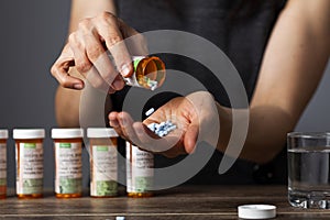 A young depressed woman is taking pills out of the medication bottle