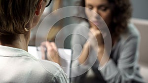 Young depressed woman talking to lady psychologist during session, mental health photo