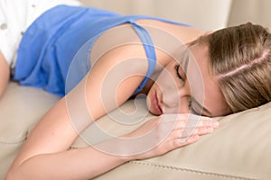 Young deprived sleeping woman lying asleep on sofa, close up