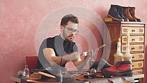 Young designer using a brush while working in shoe shop with modern interior