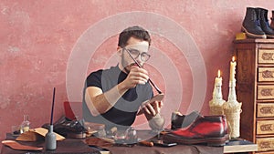 Young designer using a brush while working in shoe shop with modern interior