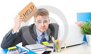 Young desperate businessman holding help sign looking worried suffering work stress at computer desk