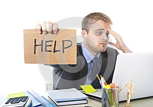 Young desperate businessman holding help sign looking worried suffering work stress at computer desk