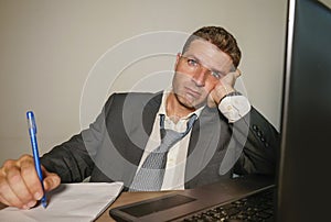Young desperate and depressed business man suffering problem and depression at office desk working with laptop computer feeling