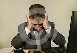 Young desperate and depressed business man suffering problem and depression at office desk working with laptop computer feeling