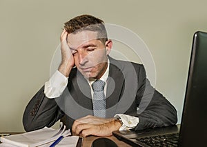 Young desperate and depressed business man suffering problem and depression at office desk working with laptop computer feeling