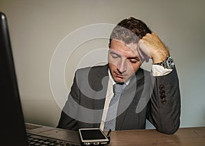 Young desperate and depressed business man suffering problem and depression at office desk working with laptop computer feeling