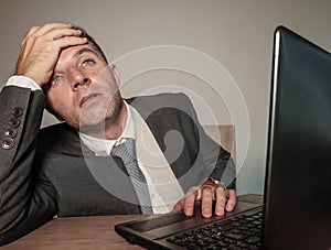 Young desperate and depressed business man suffering problem and depression at office desk working with laptop computer feeling