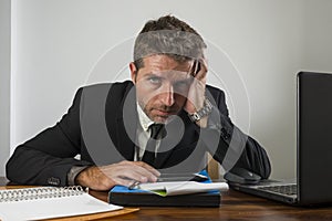 Young desperate and frustrated businessman working stressed and upset sitting at office computer desk serious feeling sad