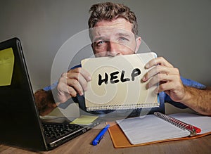 Young desperate and stressed businessman feeling overwhelmed working with laptop computer at office desk sad suffering stress aski