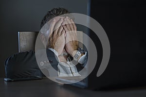 Young desperate and stressed businessman working overtime at office laptop computer desk feeling anxious and overwhelmed suffering