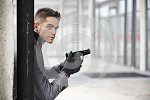 Young detective or policeman or mobster in an urban setting holding a gun