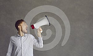 Young determined man makes a loud announcement while speaking into a loudspeaker.