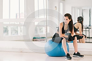 Young and determined Asian girl on fitness ball at gym with copy space, sport and healthy lifestyle concept