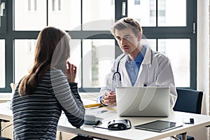 Young devoted doctor listening with attention to his patient