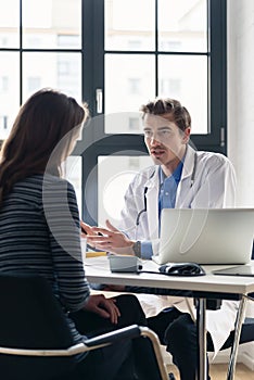 Young devoted doctor listening with attention to his patient