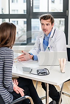 Young devoted doctor listening with attention to his patient during consultation