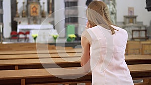 Young devoted religious woman praying in catholic church. Faithful catholic at european cathedral