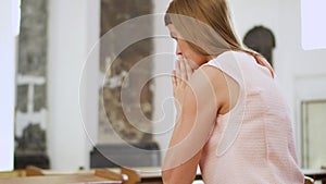 Young devoted religious woman praying in catholic church. Faithful catholic at european cathedral