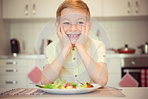 Young diligent happy boy at a table eating healthy meal