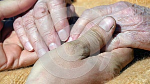 A young dirty working man`s hands comforting an elderly pair of hands of grandmother outdoor