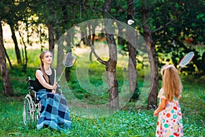 A young disabled girl plays badminton with her younger sister. Interaction of a healthy person with a disabled person.