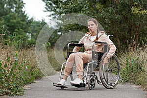 A young disabled girl sits in a wheelchair on the street. The concept of a wheelchair, disabled person, full life, paralyzed,