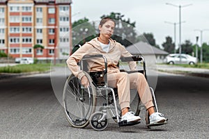 A young disabled girl sits in a wheelchair on the street. The concept of a wheelchair, disabled person, full life, paralyzed,