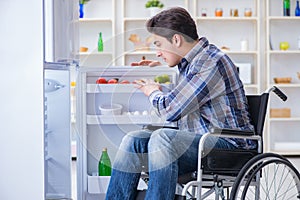 The young disabled injured man opening the fridge door