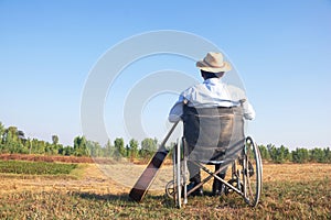 Young disabled man and field background. He is raising guitar and looking into sky