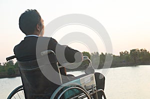 Young disabled man with field background.He is wearing sitting on wheelchair