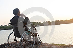 Young disabled man with field background.He is wearing sitting on wheelchair