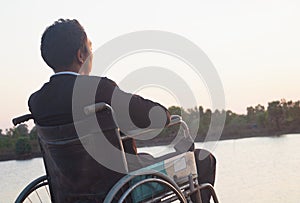 Young disabled man with field background.He is wearing sitting on wheelchair