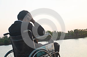 Young disabled man with river background.He is sitting on wheelchair