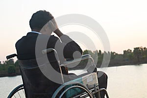 Young disabled man with river background.He is sitting on wheelchair