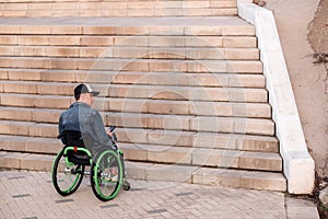 a young disabled person in a wheelchair can not enter the stairs. Accessible environment for the disabled