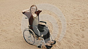 Young disabled woman on the sandy beach sitting in the wheelchair