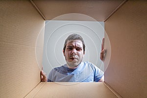 Young disappointed man is looking on gift inside cardboard box photo