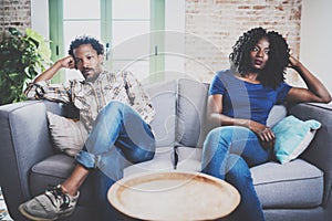 Young displeased black couple.American african men arguing with his stylish girlfriend,who is sitting on sofa on couch