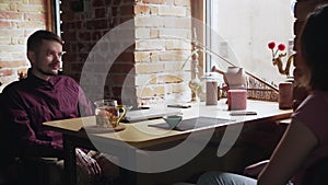 Young diverse couple smiling and speaking while drinking tea on date in cafe