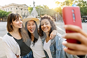 Young diverse female friends enjoying summer days taking selfie outdoors